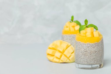 Chia tohum puding mango ile güzel gözlük yeşil nane yaprakları ile püre ve açık gri renkli - ham vejetaryen şekerli organik tatlı taze olgun tropikal meyve kesme.