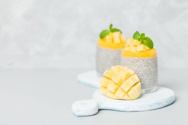 Chia tohum puding mango ile güzel gözlük yeşil nane yaprakları ile püre ve açık gri renkli - ham vejetaryen şekerli organik tatlı taze olgun tropikal meyve kesme.