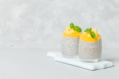 Chia tohum puding mango ile güzel gözlük yeşil nane yaprakları ile püre ve açık gri renkli - ham vejetaryen şekerli organik tatlı taze olgun tropikal meyve kesme.
