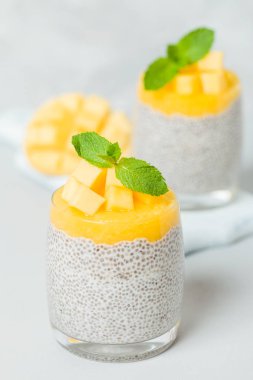 Chia tohum puding mango ile güzel gözlük yeşil nane yaprakları ile püre ve açık gri renkli - ham vejetaryen şekerli organik tatlı taze olgun tropikal meyve kesme.