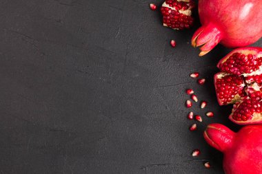 Olgun kırmızı nar closeup Fotoğrafçılık kopya alanı - üstten görünüm mevsimlik ham bütün ve kesme sulu meyve tohumları metin için boş yer karanlık ruh tarzı ile siyah zemin üzerine.