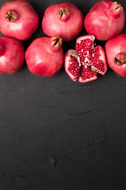 Olgun kırmızı nar closeup Fotoğrafçılık kopya alanı - üstten görünüm mevsimlik ham bütün ve kesme sulu meyve tohumları metin için boş yer karanlık ruh tarzı ile siyah zemin üzerine.