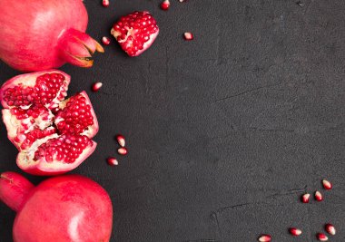 Olgun kırmızı nar closeup Fotoğrafçılık kopya alanı - üstten görünüm mevsimlik ham bütün ve kesme sulu meyve tohumları metin için boş yer karanlık ruh tarzı ile siyah zemin üzerine.