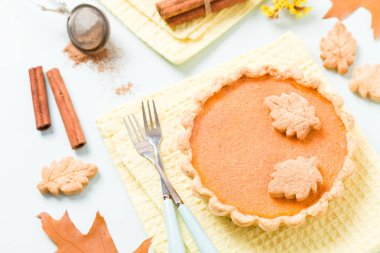 Tarçın ve çerezleri sarı sonbahar yaprakları - pastel mavi zemin üzerine sarı peçete ile kabak pasta üstten görünüm kapatmak kadar mevsimlik Amerikan geleneksel tatlı pişmiş gıda fotoğrafçılığı.