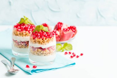 Nar parfe - granola pul, yoğurt ve olgun meyve şekerli organik katmanlı tatlı güzel gözlük kopya alanı pastel mavi zemin üzerine tohum. Doğal vejetaryen sağlıklı gıda.