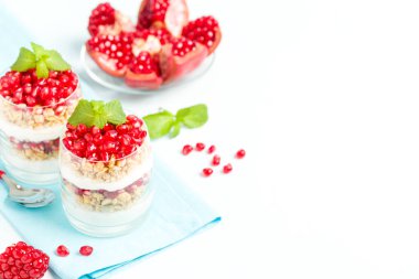 Nar parfe - granola pul, yoğurt ve olgun meyve şekerli organik katmanlı tatlı güzel gözlük kopya alanı pastel mavi zemin üzerine tohum. Doğal vejetaryen sağlıklı gıda.