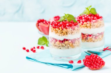 Nar parfe - granola pul, yoğurt ve olgun meyve şekerli organik katmanlı tatlı güzel gözlük kopya alanı pastel mavi zemin üzerine tohum. Doğal vejetaryen sağlıklı gıda.
