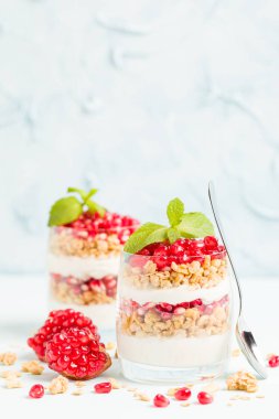 Nar parfe - granola pul, yoğurt ve olgun meyve şekerli organik katmanlı tatlı güzel gözlük kopya alanı pastel mavi zemin üzerine tohum. Doğal vejetaryen sağlıklı gıda.