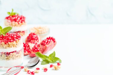 Nar parfe - granola pul, yoğurt ve olgun meyve şekerli organik katmanlı tatlı güzel gözlük kopya alanı pastel mavi zemin üzerine tohum. Doğal vejetaryen sağlıklı gıda.