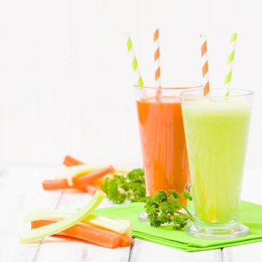 Havuç ve kereviz suyu ile taze sebze kabuğu plakaları ahşap arka plan - ham vejetaryen vitamini içmek için sağlıklı beslenme kavramı üzerinde. Organik yiyecek ve içecek maydanoz yaprakları ile süslenmiş.