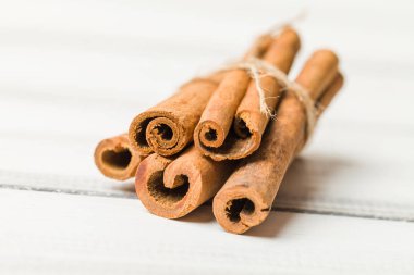 Paket Beyaz ahşap zemin üzerine tarçın bağladı. Kuru ağaç kabuğu - aromatik ve lezzetli yemek pişirmek için aromalar çeşni yığını makro fotoğrafçılık.