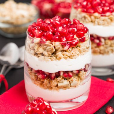 Nar parfe - granola pul, yoğurt ve olgun meyve şekerli organik katmanlı tatlı güzel gözlük kopya alanı siyah zemin üzerine tohum. Karanlık ruh tarzı doğal sağlıklı gıda.