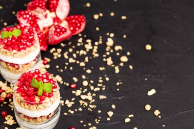 Nar parfe - granola pul, yoğurt ve olgun meyve şekerli organik katmanlı tatlı güzel gözlük kopya alanı siyah zemin üzerine tohum. Karanlık ruh tarzı doğal sağlıklı gıda.