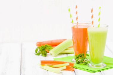 Havuç ve kereviz suyu ile taze sebze kabuğu plakaları ahşap arka plan - ham vejetaryen vitamini içmek için sağlıklı beslenme kavramı üzerinde. Organik yiyecek ve içecek maydanoz yaprakları ile süslenmiş.