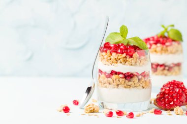 Nar parfe - granola pul, yoğurt ve olgun meyve şekerli organik katmanlı tatlı güzel gözlük kopya alanı pastel mavi zemin üzerine tohum. Doğal vejetaryen sağlıklı gıda.