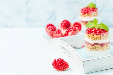 Nar parfe - granola pul, yoğurt ve olgun meyve şekerli organik katmanlı tatlı güzel gözlük kopya alanı pastel mavi zemin üzerine tohum. Doğal vejetaryen sağlıklı gıda.
