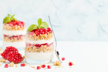 Nar parfe - granola pul, yoğurt ve olgun meyve şekerli organik katmanlı tatlı güzel gözlük kopya alanı pastel mavi zemin üzerine tohum. Doğal vejetaryen sağlıklı gıda.