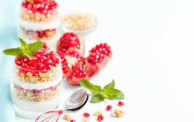 Nar parfe - granola pul, yoğurt ve olgun meyve şekerli organik katmanlı tatlı güzel gözlük kopya alanı pastel mavi zemin üzerine tohum. Doğal vejetaryen sağlıklı gıda.