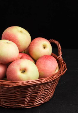 Hasır sepet kopya alanı - organik tarım sarı ve kırmızı meyve ile dikey banner siyah zemin üzerine olgun ham elma. Sağlıklı vejetaryen şekerli tatlı doğal beslenme konsepti için.