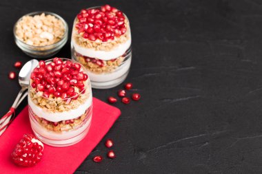 Nar parfe - granola pul, yoğurt ve olgun meyve şekerli organik katmanlı tatlı güzel gözlük kopya alanı siyah zemin üzerine tohum. Karanlık ruh tarzı doğal sağlıklı gıda.