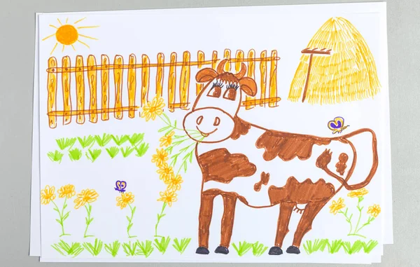 Kid drawing of cute white and brown cow on yard with green grass, stack of hay and wooden fence - bright scribble child doodle of rustic spotted livestock. Felt-tip pen picture of farm milky animal.