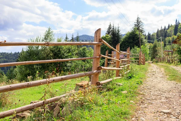 Wooden village fence in mountains near dirt road. — Stock Photo, Image