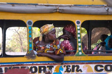 Dakar, Senegal - 27 Mayıs 2014: Ülkenin tipik renkli kostümlü kadınları, kentteki bir istasyonda eski bir ulaşım otobüsünün camlarına bakıyorlar