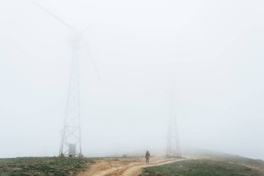 Büyük rüzgar çiftlikleri, sis, dağlarda yüksek ile kaplı bir adam bakar