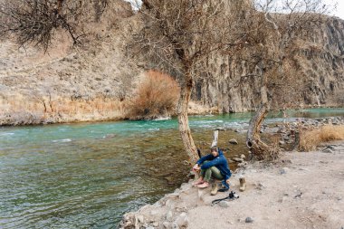 Bir dağ dere kıyısında dinlenme bir kamera ile bir gezgin. O onun giysi ve ayakkabı kurur.