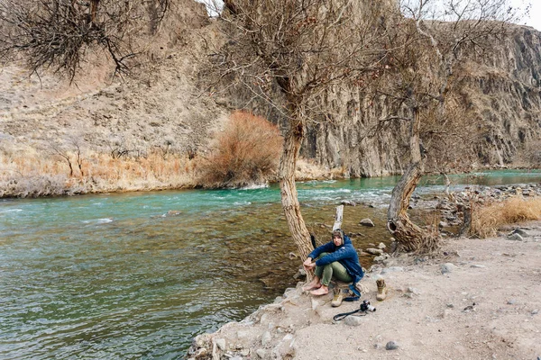 Bir dağ dere kıyısında dinlenme bir kamera ile bir gezgin. O onun giysi ve ayakkabı kurur.