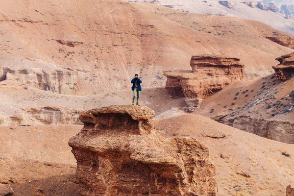 Bir kamera ile neşeli bir gezgin Kazakistan'daki Çarın Kanyonu'uçurumun kenarında duruyor. 