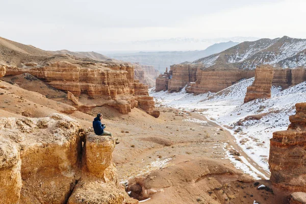 Bir kamera ile neşeli bir gezgin Çarın Kanyonu Kazakistan'ın ' bir uçurumun kenarına oturur. Analog Amerikan Grand Canyon