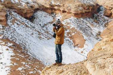 Bir kamera ile neşeli bir gezgin Kazakistan'daki Çarın Kanyonu'uçurumun kenarında duruyor. Analog Amerikan Grand Canyon