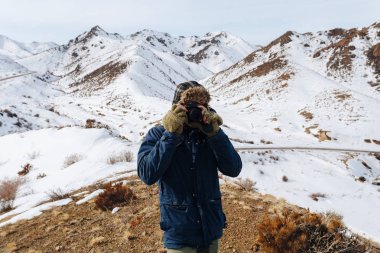 Kazakistan karla kaplı dağlar arasında neşeli bir gezgin bir kamera ile standları