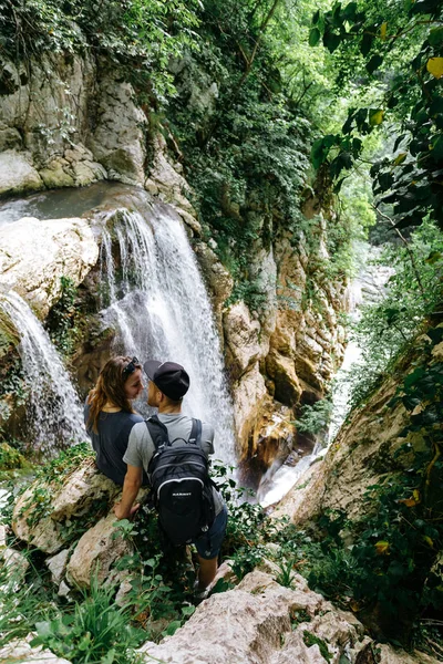 Una giovane coppia seduta sul bordo di una grande cascata nella gola di Agur . — Foto Stock