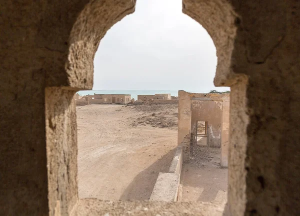 Ruined ancient old Arab pearling and fishing town Al Jumail, Qatar. The desert at coast of Persian Gulf. Abandoned mosque with minaret. Deserted village. A view out of minaret\'s window to the sea