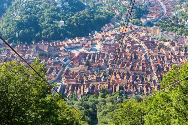 Brasov historical city centre as seen by tourists from Mount Tampa Cable Car. Medieval town in a valley - town hall, Ratusz, high spires, churches, houses, streets, and red tiled roofs, Transylvania.