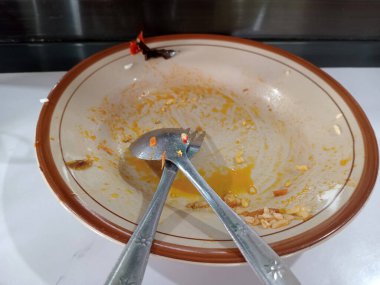 Çatal ve kaşıkla dolu boş bir kâse, yemek artıkları..