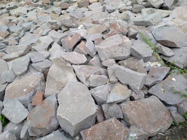 Bazı yeşil bitkilerle düzensiz şekilli gri ve kahverengi kayalar yığını..