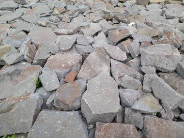 Gri ve kahverengi kaya yığınlarının boyut ve şekli değişkendir..