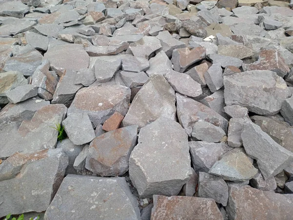 Gri ve kahverengi kaya yığınlarının boyut ve şekli değişkendir..