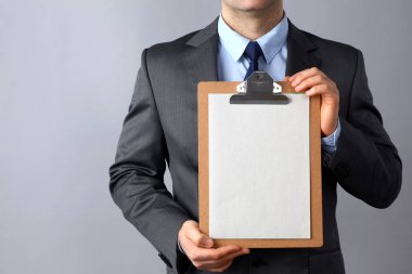 Ayakta gri arka plan üzerinde izole klasörle genç adam