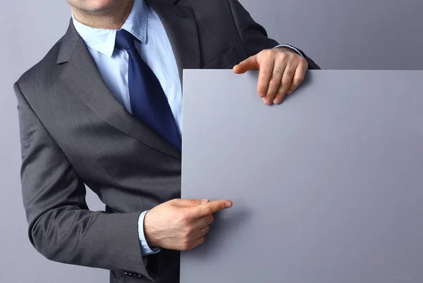 Empresario sosteniendo un tablero en blanco aislado sobre fondo gris — Foto de Stock