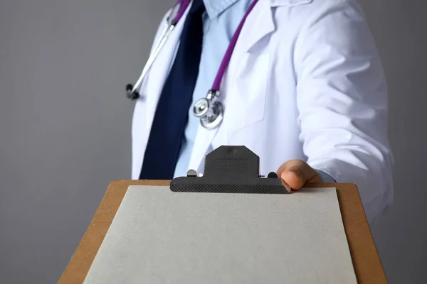 Ο γιατρός σε ένα άσπρο παλτό με ένα ιατρικό στηθοσκόπιο κρατώντας ένα φάκελο — Φωτογραφία Αρχείου