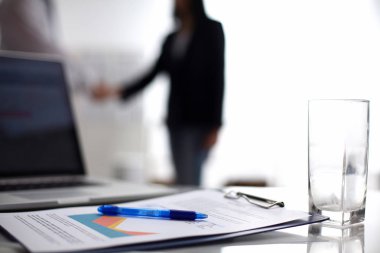 Dizüstü bilgisayar ile ağıl üstünde okul sırası, arka planda duran iki iş adamları