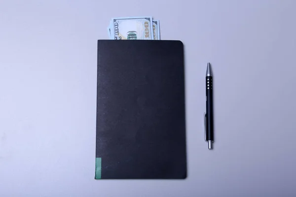 Book with money and pen top view — Stock Photo, Image