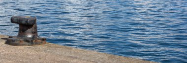 Arka planda mavi deniz suyuyla iskelede bollar