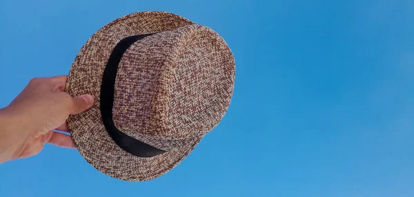 hand with hat on the background of the sky