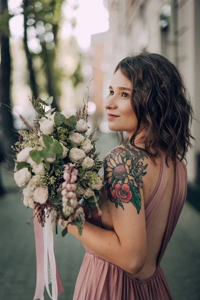 Happy and smiling woman with bouquet of flowers in a pink wedding dress and wedding ring. Bride, Bridesmaid. Modern photo style