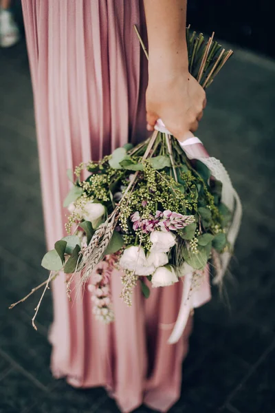 Happy and smiling woman with bouquet of flowers in a pink wedding dress and wedding ring. Bride, Bridesmaid. Modern photo style